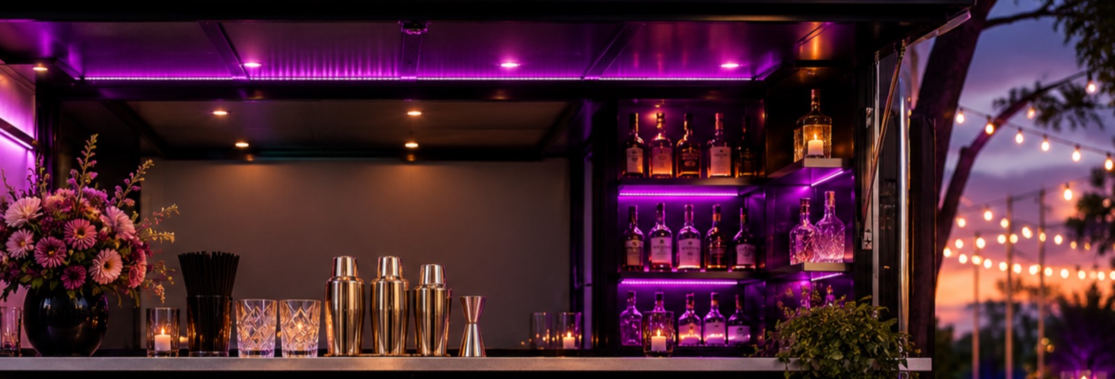 The K2 Cocktails mobile bar set up at dusk, lit in purple neon with string lights behind it